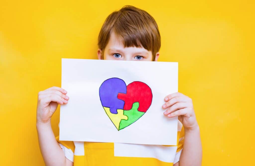 Kid boy hands holding puzzle heart, child mental health concept, world autism awareness day