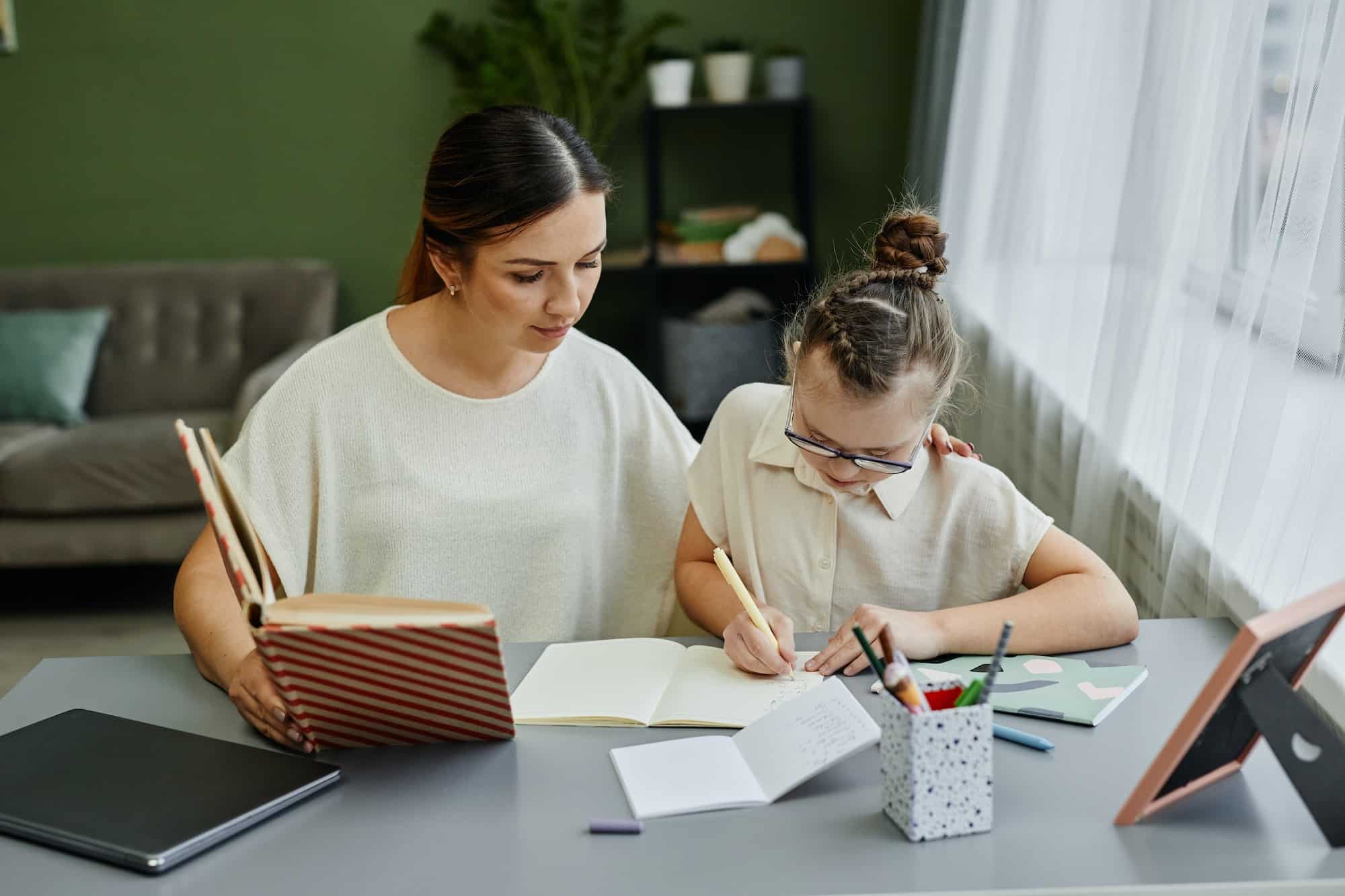 Mother Helping Girl with Down Syndrome Studying